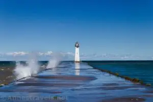 Waves on the pier and lighthouse at Sodus Point Beach Park, Sodus, New York